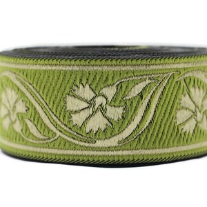 May include: A roll of decorative ribbon featuring a floral design. The ribbon has a light green background with a cream-colored floral pattern. The edges are black. This ribbon is suitable for crafts and embellishments.