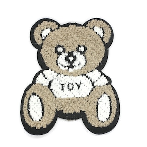 Op de afbeelding: Een bruine teddybeer pluche patch met een wit shirt waarop "TOBY" staat.