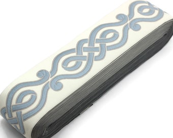 May include: A roll of white trim with a blue, decorative, woven pattern. The trim is folded and rolled up.
