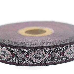 May include: A black and silver trim ribbon with a pink floral pattern. The ribbon is rolled up and ready to be used for crafting or decorating.