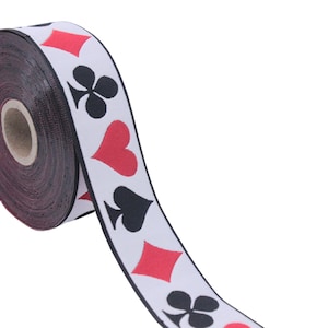 May include: A roll of white ribbon with black and red playing card symbols printed on it. The symbols include hearts, spades, clubs, and diamonds.