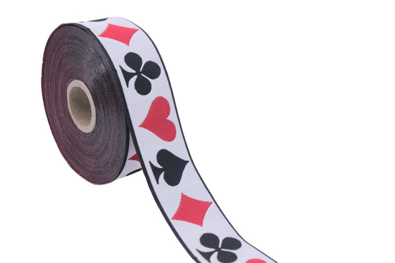May include: A roll of white ribbon with black and red playing card symbols printed on it. The symbols include hearts, spades, clubs, and diamonds.