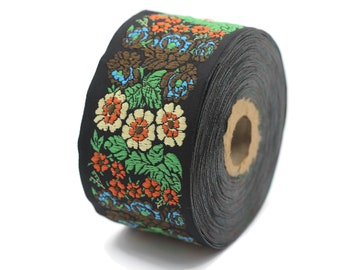 Könnte beinhalten: Eine Rolle schwarzer Stoffbesatz mit einem floralen Muster in Orange-, Grün-, Blau- und Weißtönen.