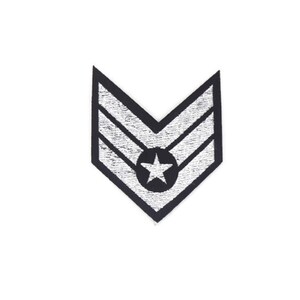 May include: A silver embroidered military rank patch with two chevrons and a star in the center.