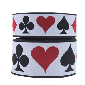 May include: Two rolls of white elastic with black trim. The elastic has a repeating pattern of red hearts, black spades, black clubs, and red diamonds.