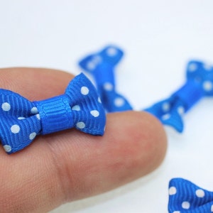 May include: Blue and white polka dot bow with a satin finish. The bow is small and is perfect for adding a touch of whimsy to any project.