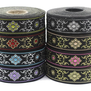 Könnte beinhalten: Ein Stapel schwarzes Band mit goldenen und silbernen Stickereien. Das Band hat ein sich wiederholendes Muster einer Blume mit einer Mitte in verschiedenen Farben, darunter Rot, Blau, Grün, Pink und Gelb.