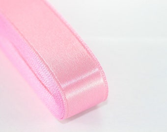 May include: A close-up of a pink satin ribbon. The ribbon is folded in half and the edges are visible.