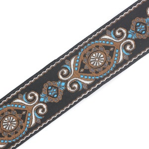 May include: Black woven trim with a white and brown paisley design. The trim features a repeating pattern of stylized floral motifs and swirls.