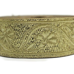 May include: A spool of gold-colored embroidered trim. The trim features a repeating floral and leaf pattern. The trim is likely made of a metallic thread, giving it a shiny appearance. The trim is suitable for sewing and crafting projects.
