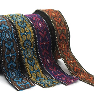 May include: Four rolls of decorative trim with intricate patterns in shades of blue, gold, purple, and orange. The trim is woven with a black background and features a repeating geometric design.