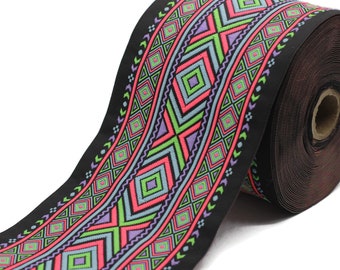 May include: A roll of black ribbon with a colorful geometric pattern. The design features repeating diamond and zigzag shapes in pink, green, purple, and blue. The ribbon is likely used for crafts or decorative purposes.