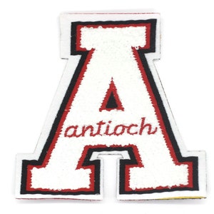 Puede incluir: Letra A de fieltro blanco con contorno rojo y ribete negro. La palabra "antioch" está bordada en rojo debajo de la letra.