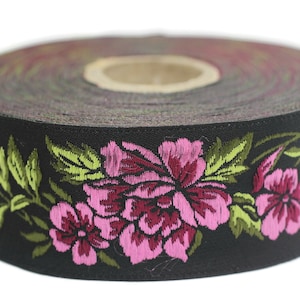 Puede incluir: Un rollo de cinta negra con un patr&oacute;n floral. La cinta est&aacute; decorada con flores bordadas de color rosa y verde.