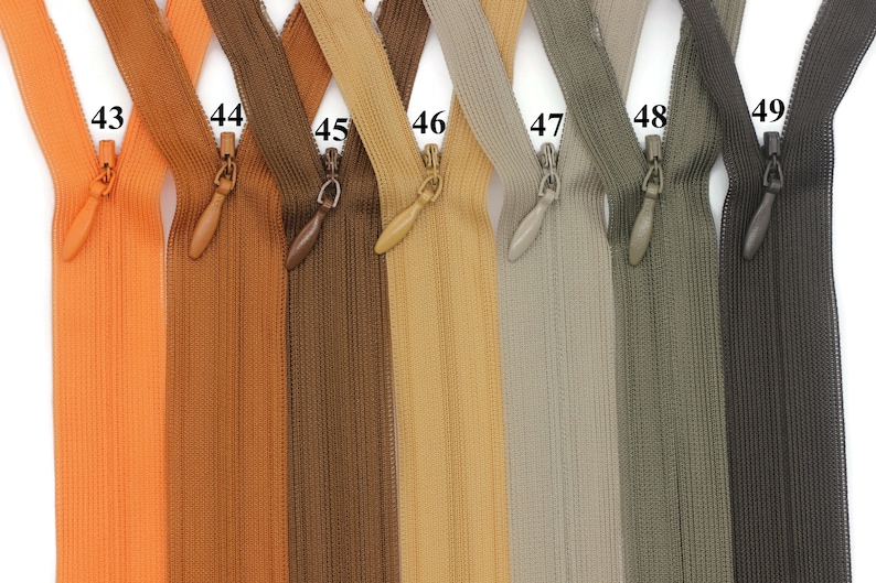 May include: Seven zipper pulls in various colors, including orange, brown, beige, gray, green, and black. The zipper pulls are numbered 43 through 49.