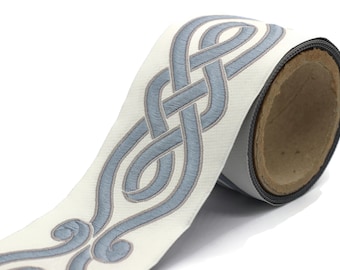 May include: A roll of white fabric trim with a blue embroidered Celtic knot design.