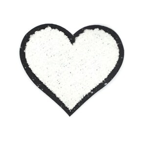 Può includere: Cuore di feltro bianco con contorno nero. Il cuore è un design semplice senza altri dettagli.