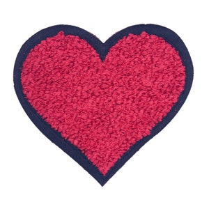 Puede incluir: Un parche rojo en forma de corazón con una superficie texturizada y un borde azul oscuro. El parche está aislado sobre un fondo blanco, mostrando su forma y contraste de color.
