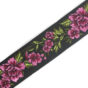 Puede incluir: Borde de tela negro con un dise&ntilde;o floral rosa y verde. El borde presenta un patr&oacute;n repetitivo de flores y hojas.