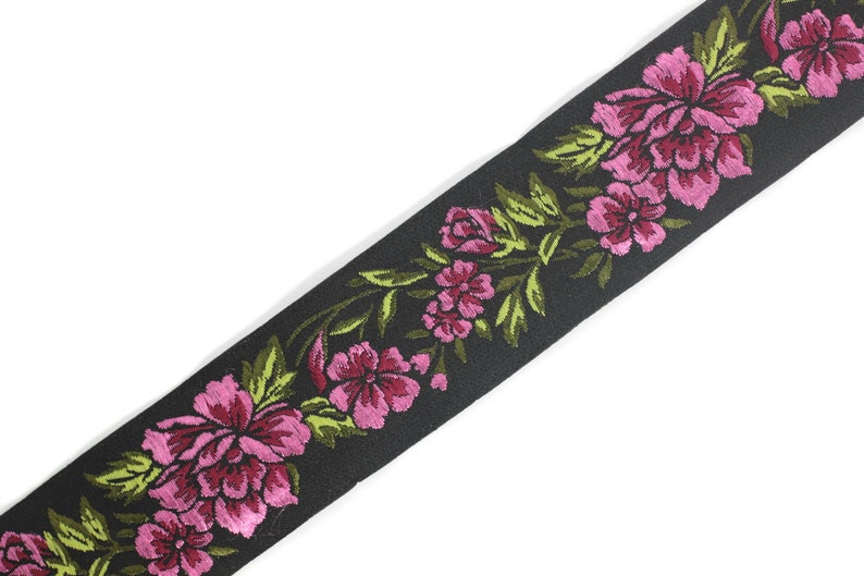 Puede incluir: Borde de tela negro con un dise&ntilde;o floral rosa y verde. El borde presenta un patr&oacute;n repetitivo de flores y hojas.