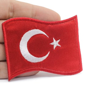 May include: A red fabric patch with a white crescent moon and star, representing the flag of Turkey.