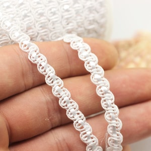 Puede incluir: Borde decorativo blanco con un diseño de bucle. El borde está hecho de un material suave y flexible, perfecto para agregar un toque de elegancia a cualquier proyecto.