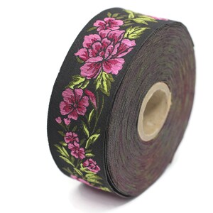 Puede incluir: Un rollo de cinta negra con un patr&oacute;n floral rosa y verde. La cinta est&aacute; enrollada y el patr&oacute;n floral es visible en el borde del rollo.