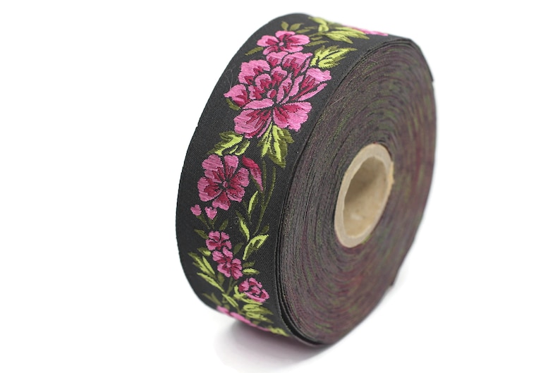 Puede incluir: Un rollo de cinta negra con un patr&oacute;n floral rosa y verde. La cinta est&aacute; enrollada y el patr&oacute;n floral es visible en el borde del rollo.