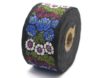 Könnte beinhalten: Schwarzer Stoffbesatz mit einem floralen Muster mit blauen, weißen, roten und grünen Blumen. Der Besatz ist auf einer Spule aufgerollt.