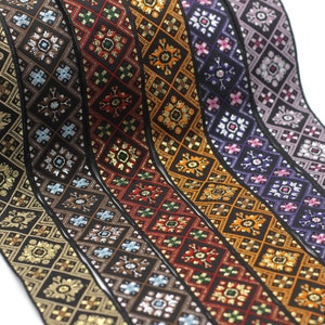 Könnte beinhalten: Nahaufnahme von sechs verschiedenen gemusterten Borten mit goldenen Akzenten. Die Borten sind schwarz mit verschiedenen Farben, darunter Rot, Orange, Lila und Blau. Die Borten haben ein geometrisches Muster mit einer Diamantform.