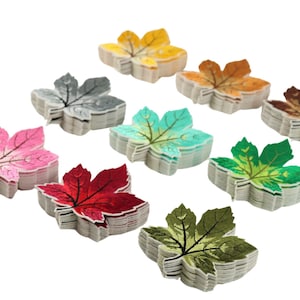 Pode incluir: Conjunto de dez patches de folha de bordo de feltro bordados em várias cores, incluindo rosa, vermelho, verde, amarelo, marrom e cinza. As folhas estão empilhadas umas sobre as outras.