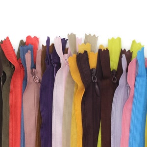May include: Assortment of colorful zipper tapes in various shades of pink, red, blue, green, yellow, brown, and gray. The zipper tapes are arranged in a row and are ready to be used for sewing projects.
