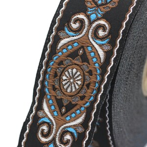 May include: A roll of black trim with a brown and blue patterned design. The trim features a repeating pattern of swirls and dots.