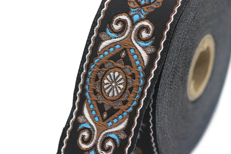May include: A roll of black trim with a brown and blue patterned design. The trim features a repeating pattern of swirls and dots.
