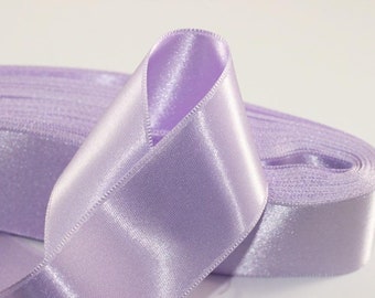 May include: A roll of lavender satin ribbon. The ribbon is folded in half and the edges are visible.