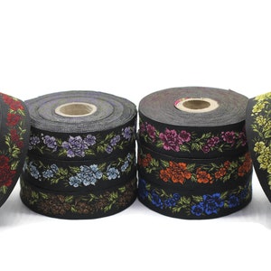 Könnte beinhalten: Vier Spulen schwarzes Band mit Blumenstickerei. Die Bänder sind in verschiedenen Farben, darunter Rot, Lila, Blau und Gelb.