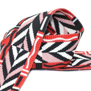 Könnte beinhalten: Gewebtes Band mit geometrischem Muster in Rot, Schwarz und Rosa.