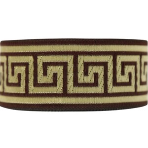 K&ouml;nnte beinhalten: Braunes elastisches Band mit einem goldenen griechischen Schl&uuml;sselmuster.