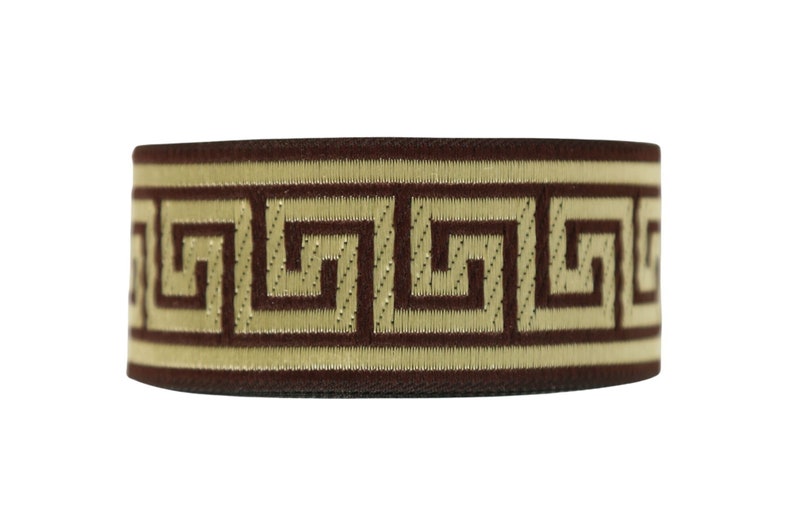 K&ouml;nnte beinhalten: Braunes elastisches Band mit einem goldenen griechischen Schl&uuml;sselmuster.
