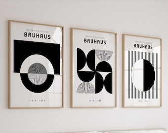 May include: Three framed Bauhaus art prints with geometric black and white designs. Each print features the text "MASTER COLLECTION BAUHAUS" and the dates "1919 - 1933". The prints are displayed above a bed with white bedding.