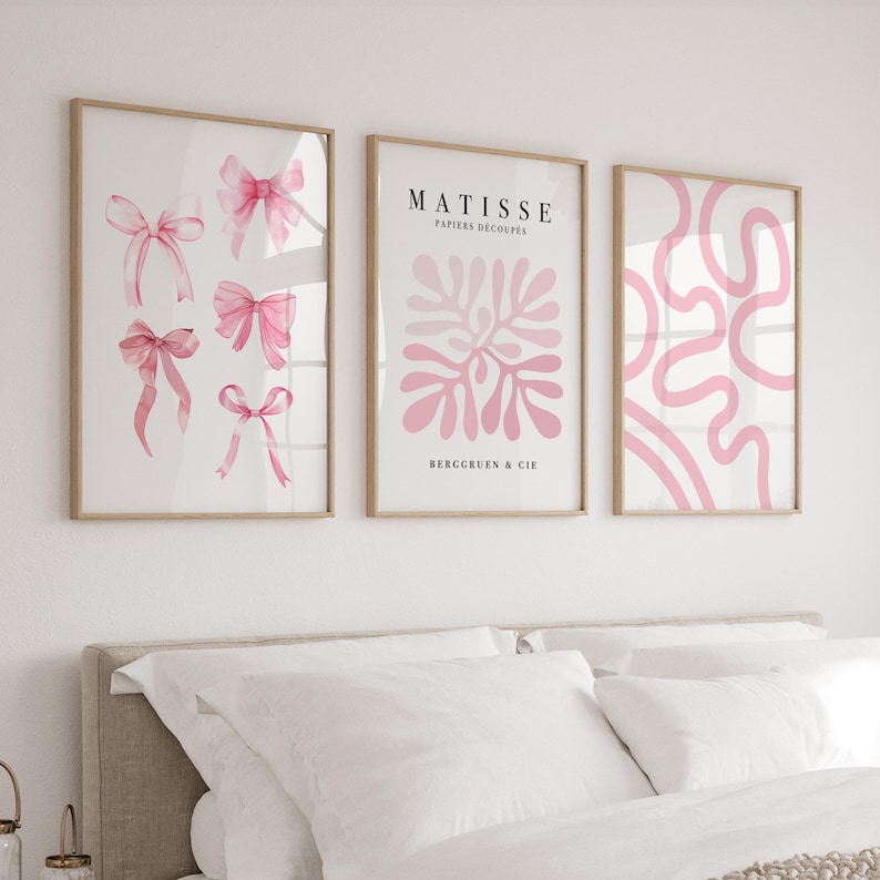 K&ouml;nnte beinhalten: Drei gerahmte Kunstdrucke mit rosafarbenen Designs. Der linke Druck zeigt rosafarbene Aquarell-Schleifen. Der mittlere Druck zeigt ein rosafarbenes abstraktes Design mit dem Text "MATISSE PAPIERS DECOUPES BERGRUEN & CIE". Der rechte Druck zeigt ein rosafarbenes abstraktes Design.