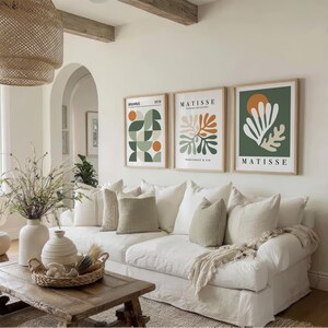 May include: A living room with a white sofa, decorative pillows, and a wooden coffee table. Three framed Matisse art prints hang above the sofa. A woven pendant light and vases with dried plants add to the room's decor.