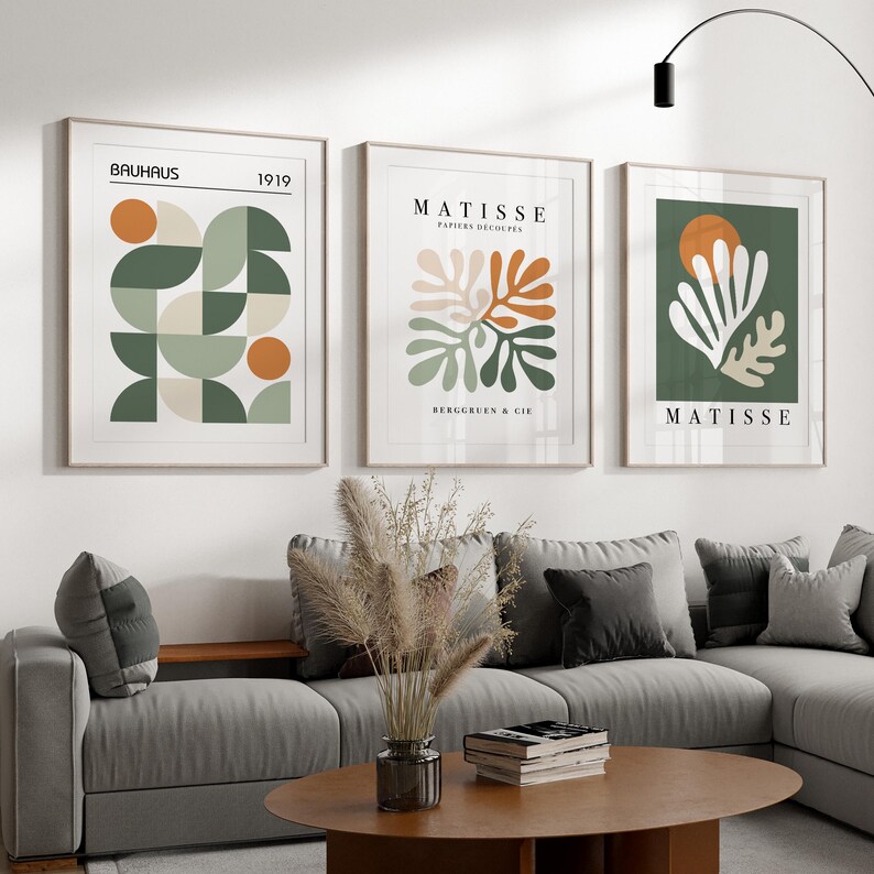 May include: Three framed art prints with abstract designs. The prints feature geometric shapes and botanical illustrations in shades of green, orange, and beige. The text "BAUHAUS 1919" and "MATISSE PAPIERS D&Eacute;COUP&Eacute;S" are visible.