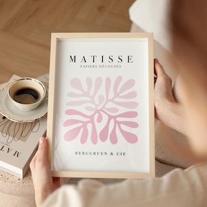 K&ouml;nnte beinhalten: Ein gerahmter Druck mit einem abstrakten Design in Rosa und dem Text "MATISSE PAPIERS DECOUPES BERGGRUEN & CIE"