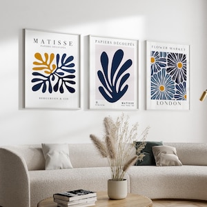 Puede incluir: Tres impresiones de arte enmarcadas con un fondo blanco y dise&ntilde;os abstractos azules y amarillos. Las impresiones se titulan "Matisse Papiers Decoupes", "Papiers Decoupes" y "Flower Market London".