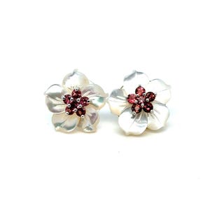 May include: A pair of flower-shaped stud earrings featuring iridescent white mother-of-pearl petals. Each earring has a cluster of five small, round, deep red garnet gemstones set in the center, creating a vibrant contrast.