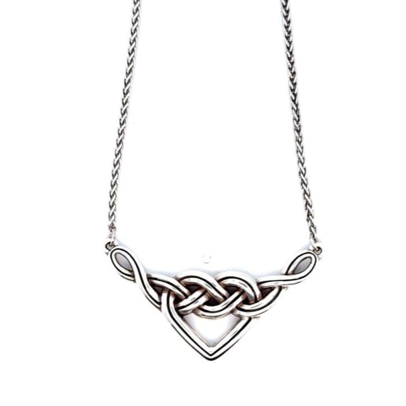 May include: A silver-toned necklace featuring a Celtic knot design. The pendant has a triangular shape with interwoven loops and a delicate chain. The necklace is displayed against a white background, highlighting the intricate details of the jewelry.
