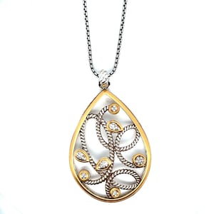 May include: A teardrop pendant necklace with a gold-tone frame and silver-tone interior. The pendant features a swirling rope design with clear gemstones. The necklace has a silver chain. The pendant is a statement piece.