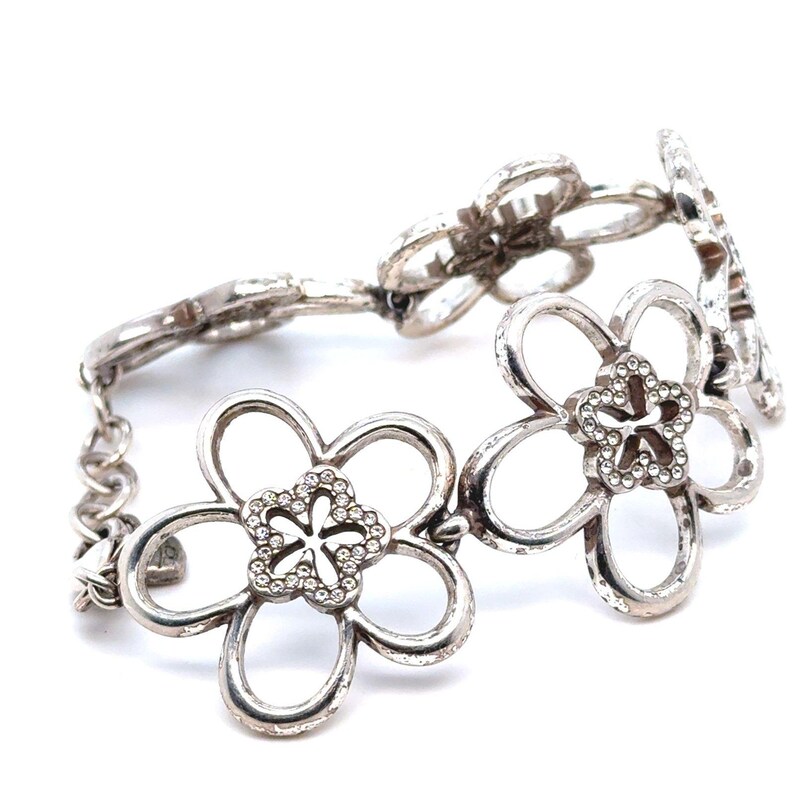 Pode incluir: Pulseira prateada com design floral. Cada flor tem cinco p&eacute;talas e um centro adornado com pequenos cristais transparentes. A pulseira &eacute; ligada com pequenos segmentos de corrente, criando um acess&oacute;rio flex&iacute;vel e elegante.