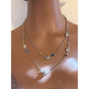 K&ouml;nnte beinhalten: Eine silberfarbene, zweireihige Halskette mit bunten, runden Edelsteinen. Die Halskette hat eine zarte Kette und verzierte, quadratische Akzente. Die Edelsteine sind in den Farbt&ouml;nen Gelb, Blau, Gr&uuml;n, Rosa und Rot gehalten.